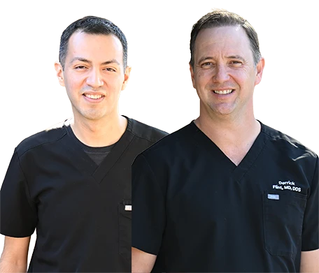 Dr. Flint and Dr. GARZA, certified Oral and Maxillofacial Surgeons, smiling with model of skull.